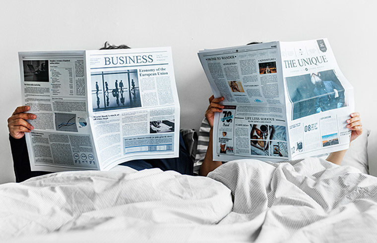 Couple in bed reading newspapers