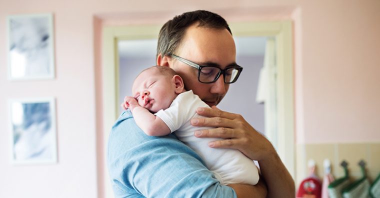 Father holding newborn baby over shoulder