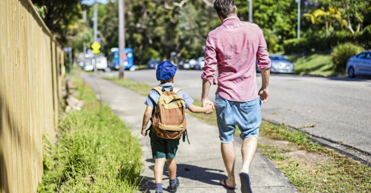 Father holding son's hand walking to school