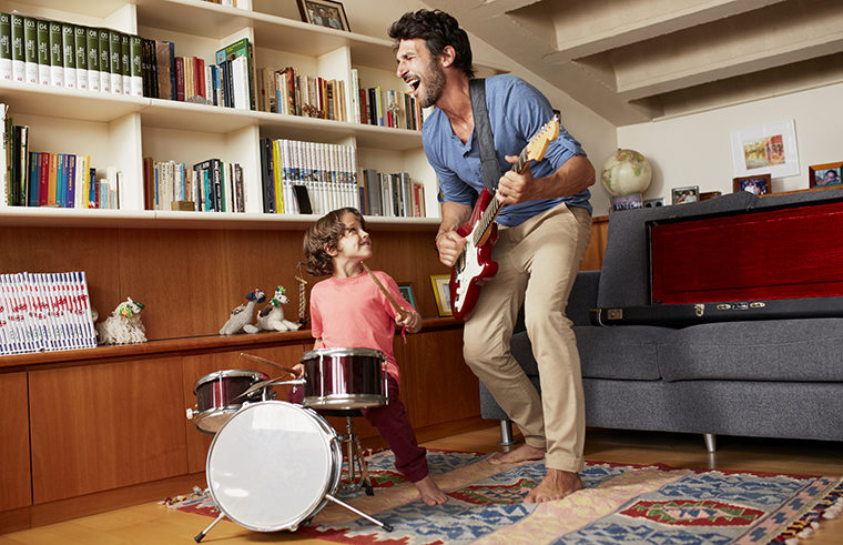 Father and son playing music with guitar and drums - feature