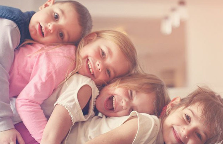 Four siblings giggling while stacked on top of each other