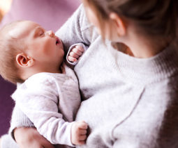 Mother holding sleeping baby in arms - feature