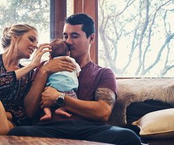 Mother and father sitting on couch holding newborn baby
