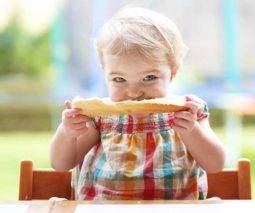 Toddler girl eating bread - feature
