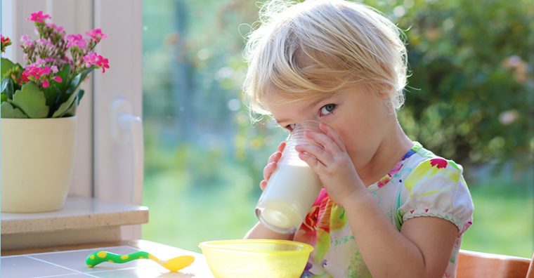 Toddler girl drinking a glass of mil