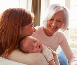 Happy grandmother visiting daughter and newborn baby - feature