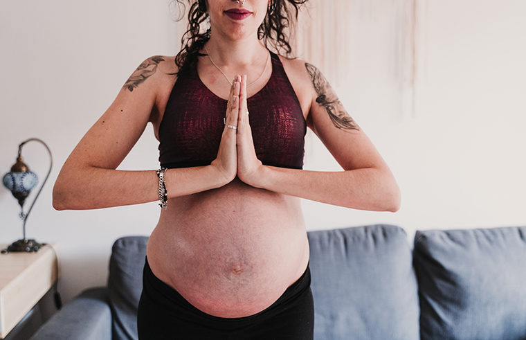 Pregnant woman doing yoga with stretch marks - feature