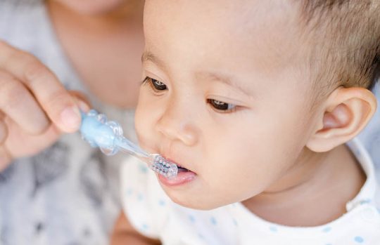 young toddler brushing teeth with toothbrush