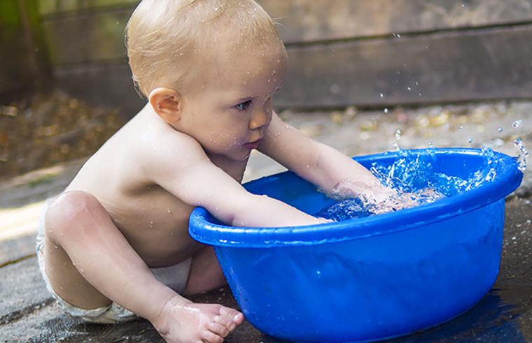 Baby playing with bucket of water - feature