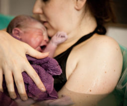 Woman holding newborn baby after home water birth