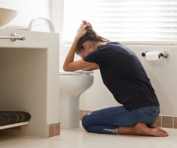 Pregnant woman suffering morning sickness, being sick in the toilet - feature