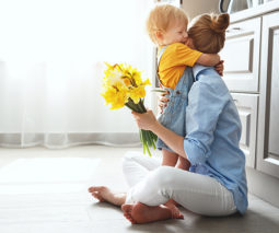 Child hugging mother with flowers