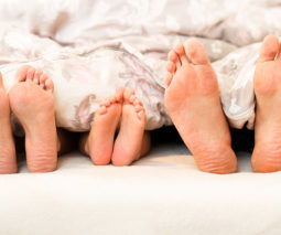 Three pairs of feet poking out from bed sheets
