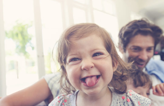 Cheeky toddler girl sticking her tongue out feature