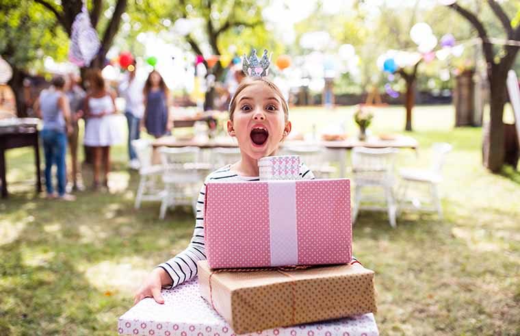 Girl holding birthday presents gifts at party - feature