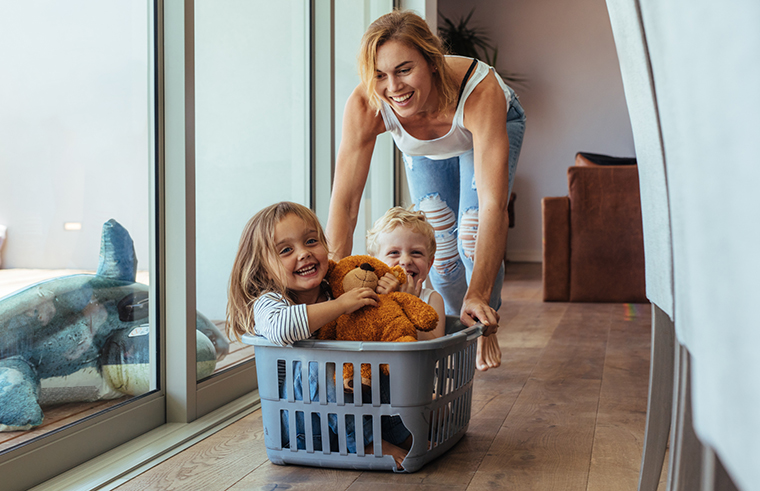 Mother pushing her children in laundry basket playing feature