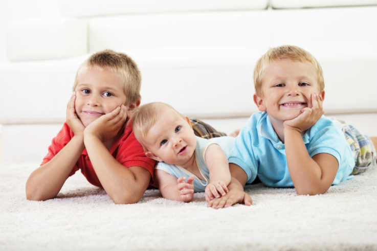 Three siblings lying on the floor together