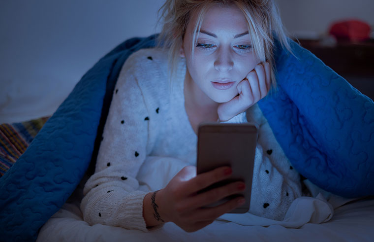 Woman using mobile in bed at night