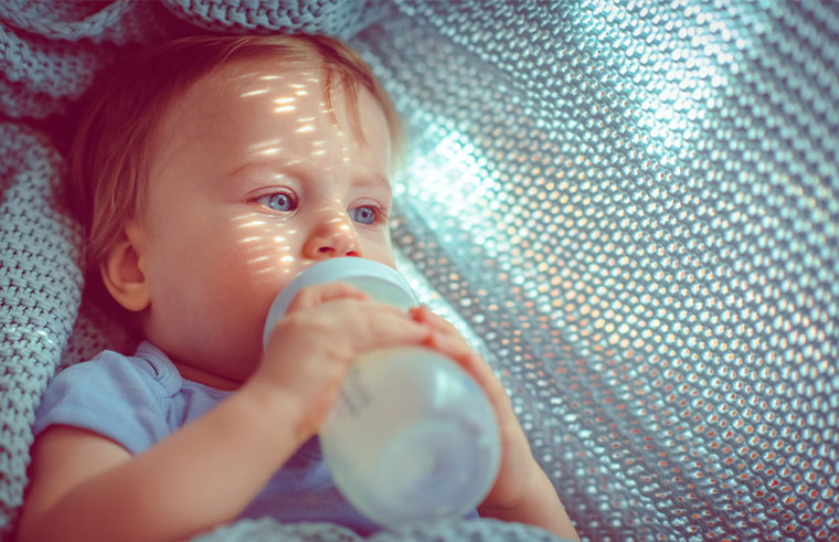 Older baby drinking milk from a bottle