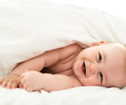 Happy baby wrapped in bed covers