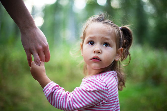 Worried girl holding her parent's hand
