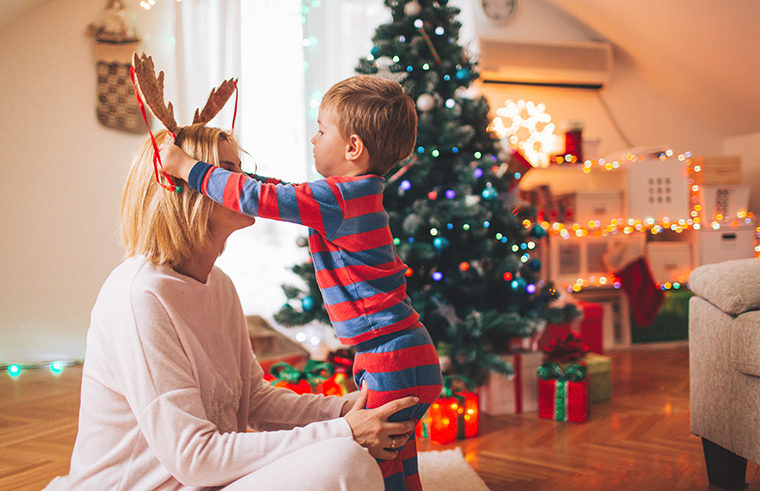 Toddler boy and mother playing in front of Christmas tree - feature