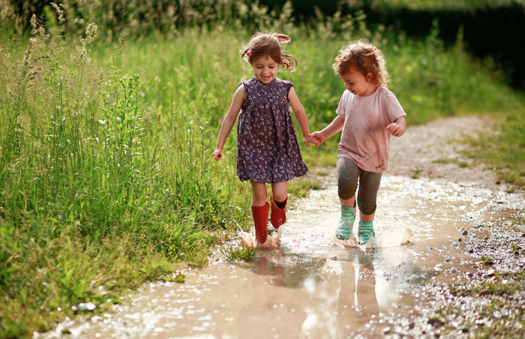 Girls wearing gumboots walking in puddle