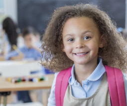 Girl in school uniform smiling in classroom - feature