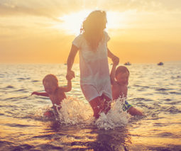 Mother and two boys sons at beach at sunset - feature