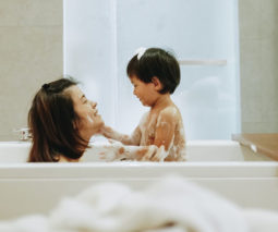 Mother and toddler son in bath together