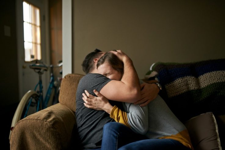 Couple hugging on couch sad