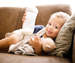 Toddler boy lying on couch with milk bottle