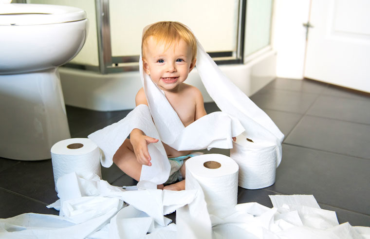 Toddler sitting in toilet paper
