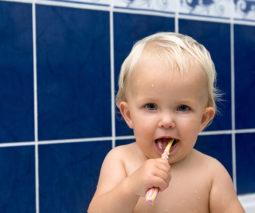 Baby girl brushing teeth with toothbrush - feature