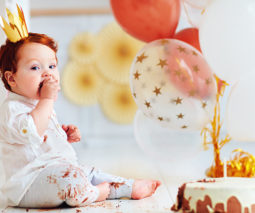 Birthday baby sitting on floor eating birthday cake