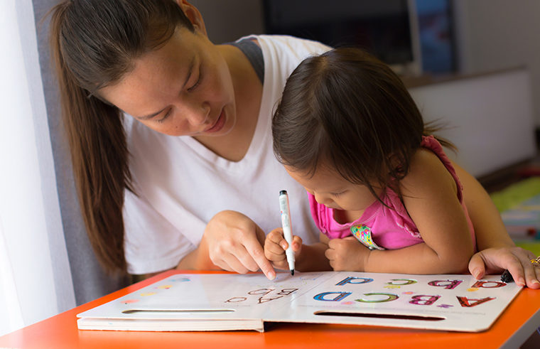 Mother teaching girl letter at home schooling