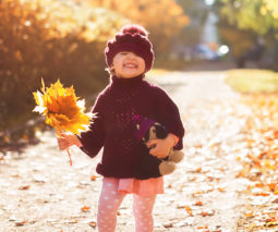 Toddler girl holding a bunch of autumn leaves feature