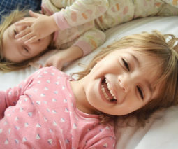Toddlers laughing in bed together