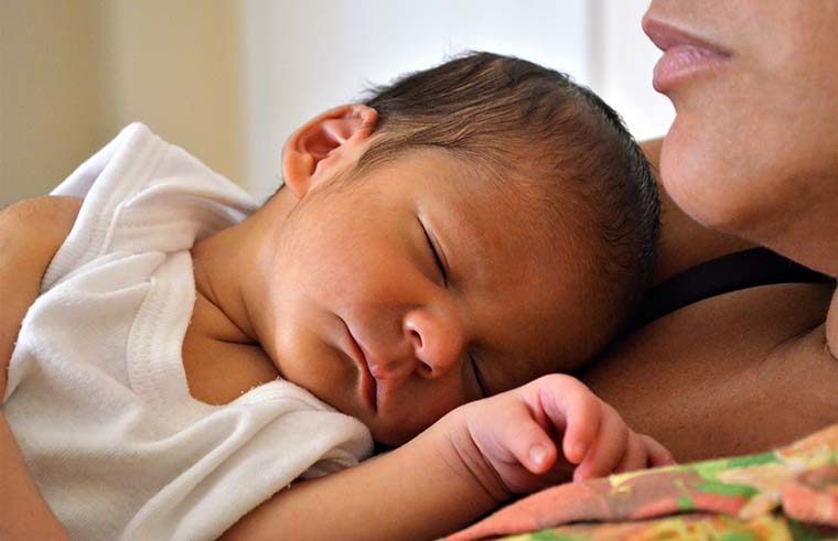 Newborn baby asleep on mother's chest - feature
