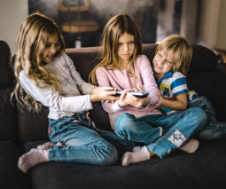 Three children on the couch fighting over the remote