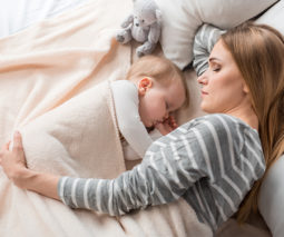 Mother asleep with baby on the bed