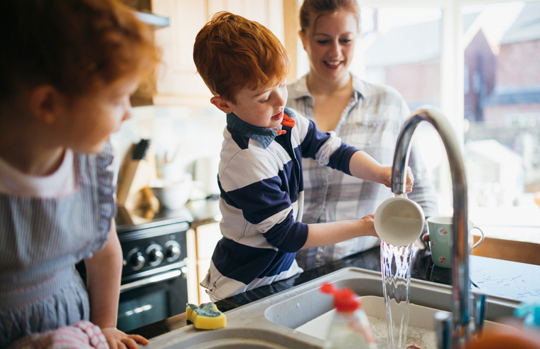 Kids washing dishes with mum supervising