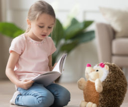 Little girl reading to her toy