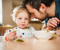 Father leaning into toddler eating food