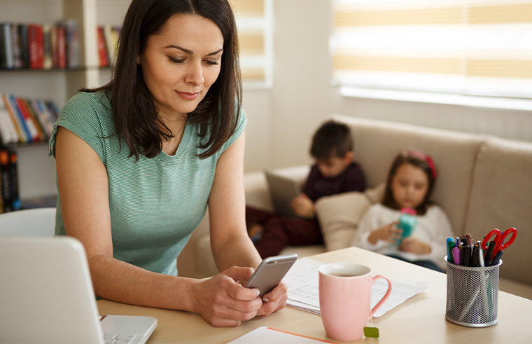 Mum on phone with kids in background on devices