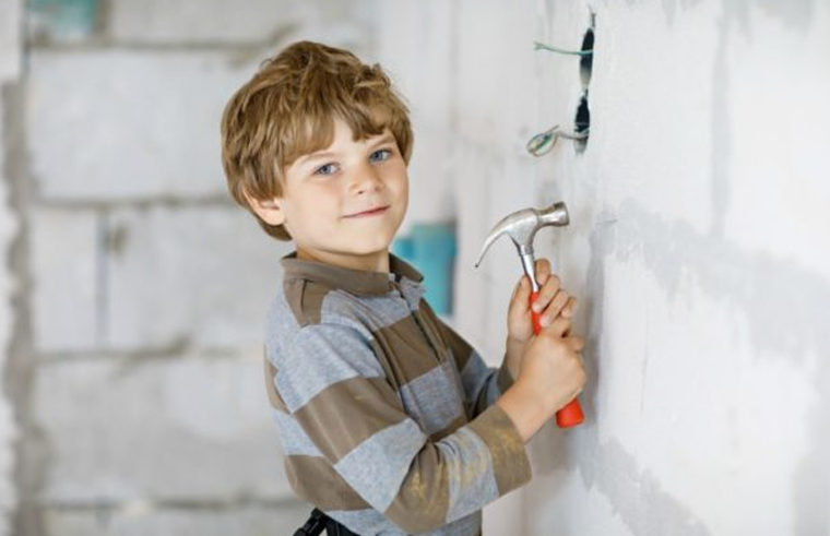 Young boy hammering a wall