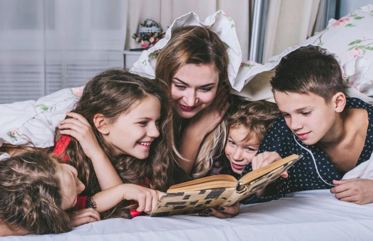 Mother reading in bed with four children