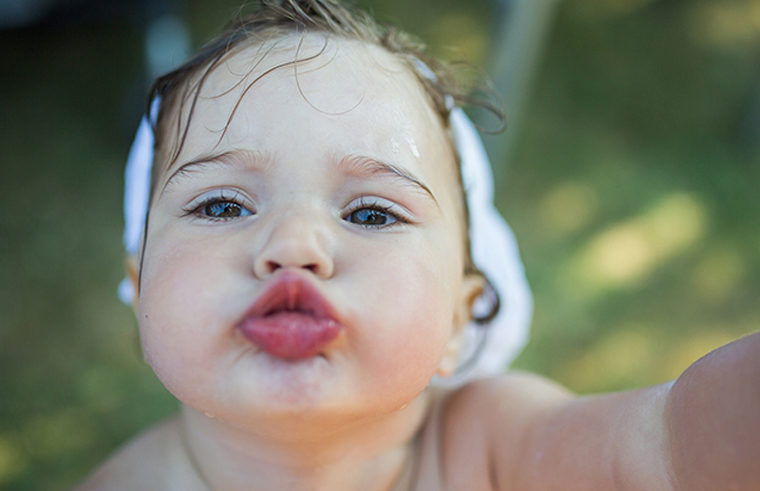 Close-up of a cute toddler girl with wet hair making a kissing face, lips pursed