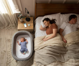 parents sleeping with baby by bed