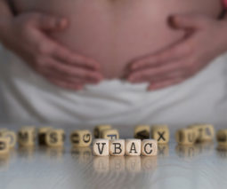 Pregnant woman holding belly with VBAC in dice